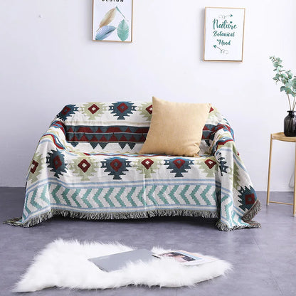 Patterned throw blanket draped over a sofa with a pillow in a room setting.