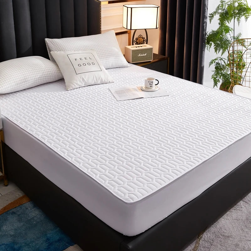 Mattress protector on a bed in a bedroom setting with pillows and a cup.