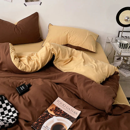 Brown and beige bedding set on a bed with a book titled 'Food Gatherer' and a checkered bag.