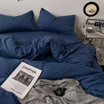Blue bedding set on a bed with a magazine and sweater in the foreground.