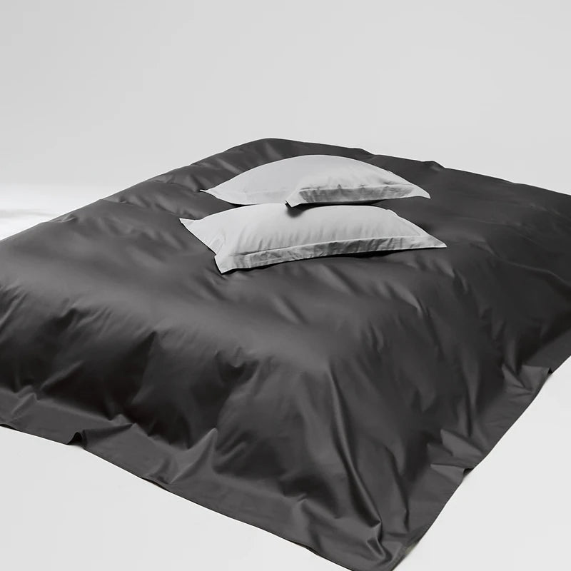 Dark gray bedding set with a white pillow on a white background