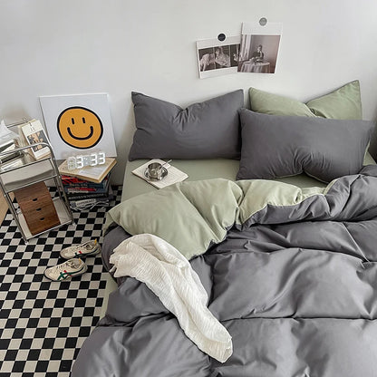Gray and green bedding set on a bed with a checkered floor and decor items in the background.