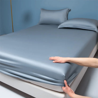 Person adjusting a fitted sheet on a bed with a blue wall background