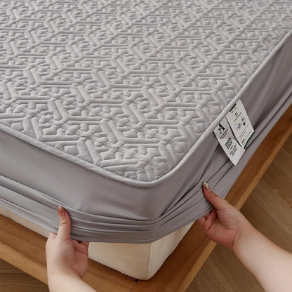 Gray mattress cover being fitted onto a bed with a geometric pattern