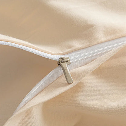 Close-up of a beige satin pillow with a gold zipper.