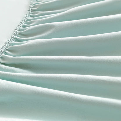 Close-up of a light blue fitted sheet with wrinkles on a white background