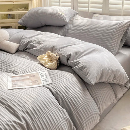 Gray striped bedding set on a bed with pillows and a small pillow on a shelf.