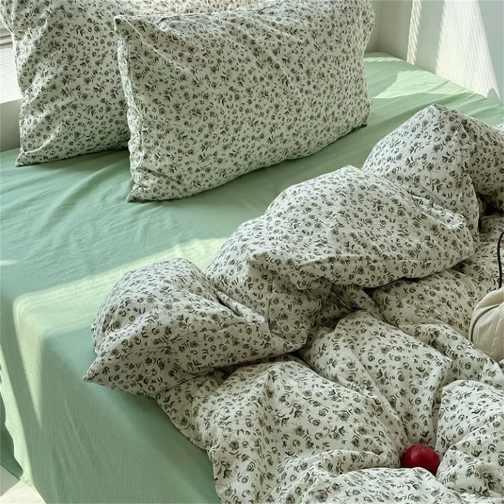 Floral-patterned pillows and comforter on a bed with green sheets