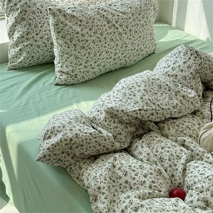 Floral-patterned pillows and comforter on a bed with green sheets