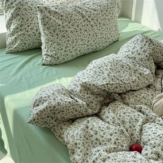 Floral-patterned pillows and comforter on a bed with green sheets