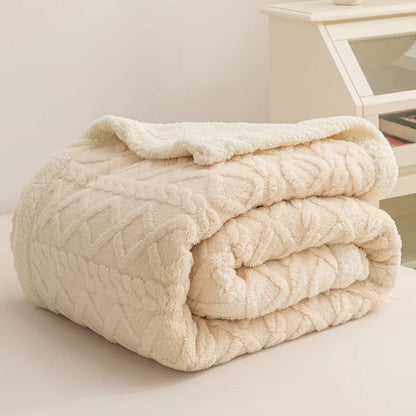 Folded cream-colored textured blanket on a light surface with a neutral background