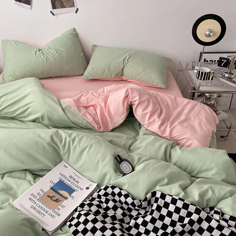 Bed with green and pink bedding, a book, and a bottle on a checkered blanket.
