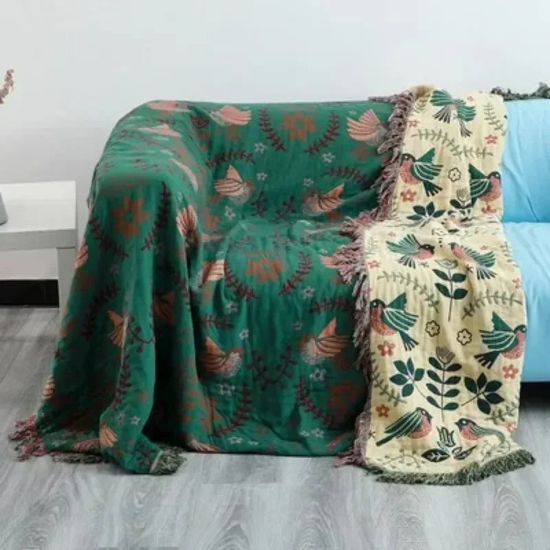 Two patterned blankets draped over a sofa with a neutral background