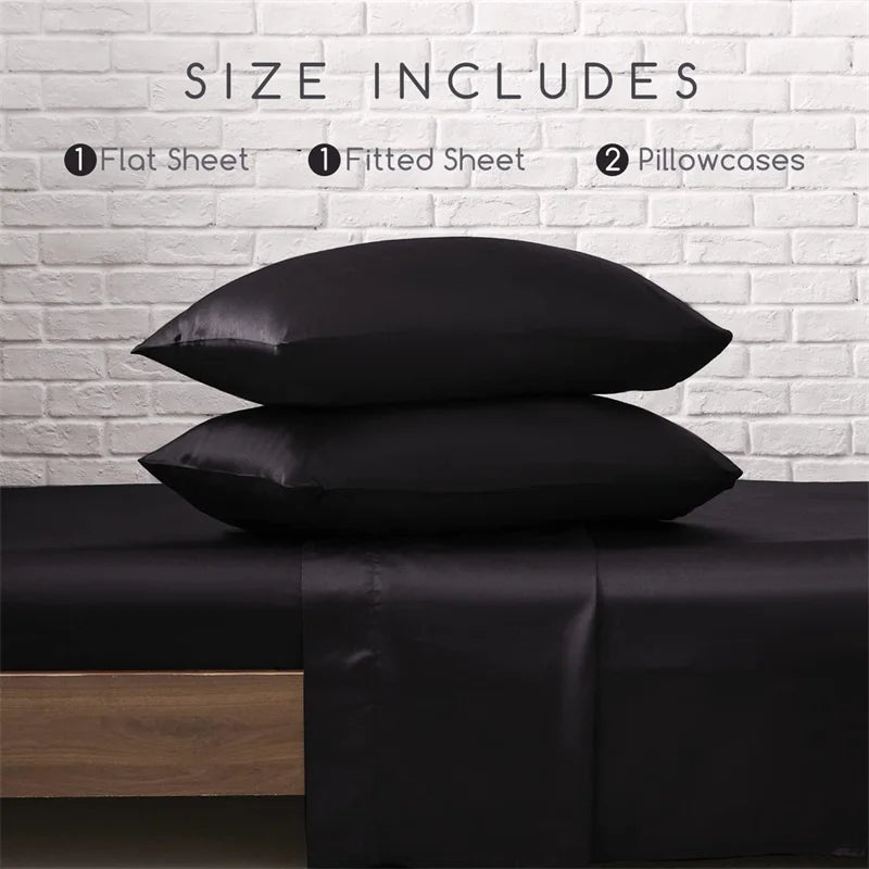 Black satin pillowcases stacked on a bed with a white brick wall background.