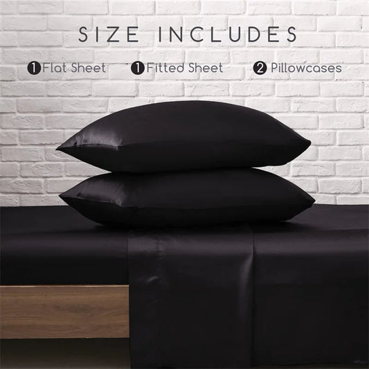 Black satin pillowcases stacked on a bed with a white brick wall background.