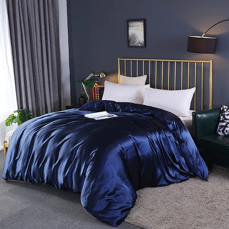 Bed with blue satin comforter and gold headboard in a bedroom setting.