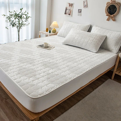 White mattress cover on a bed in a bedroom setting with pillows and decor.