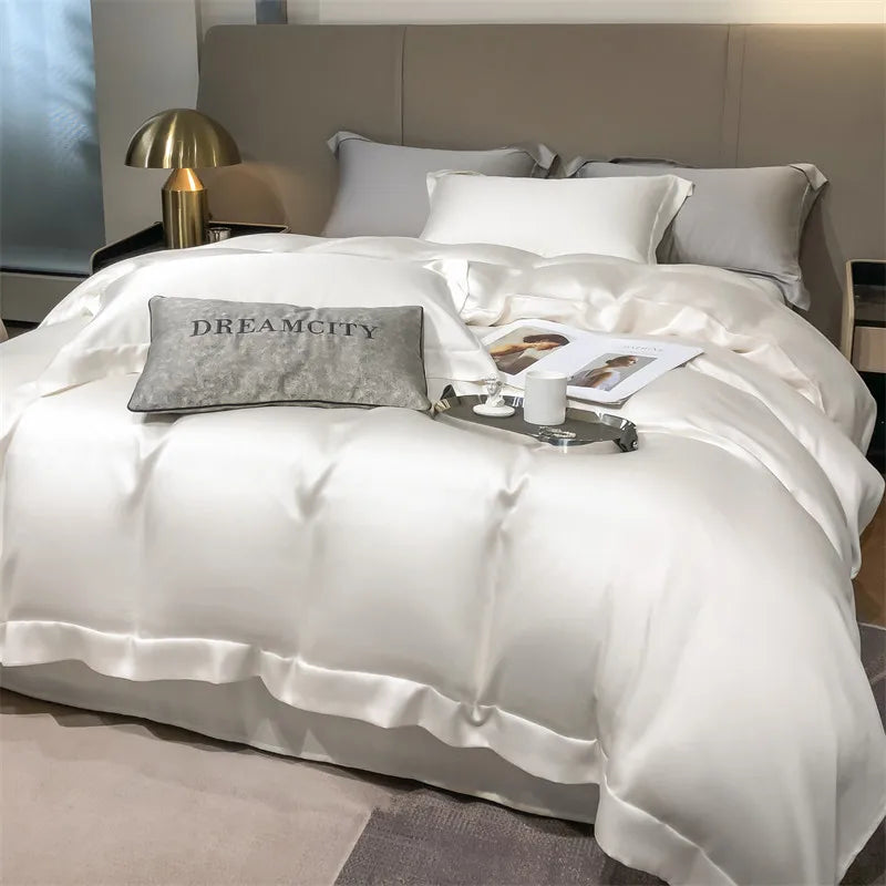 White satin comforter set on a bed with 'Dreamcity' branding, in a bedroom setting.