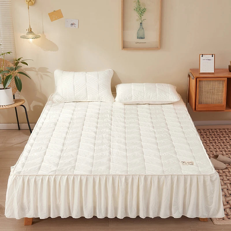White quilted mattress cover on a bed in a bedroom setting
