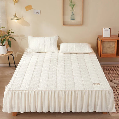 White quilted mattress cover on a bed in a bedroom setting
