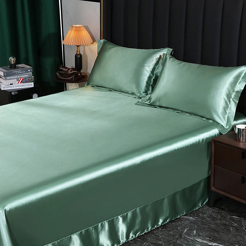 Green satin bedding set on a bed in a bedroom setting.