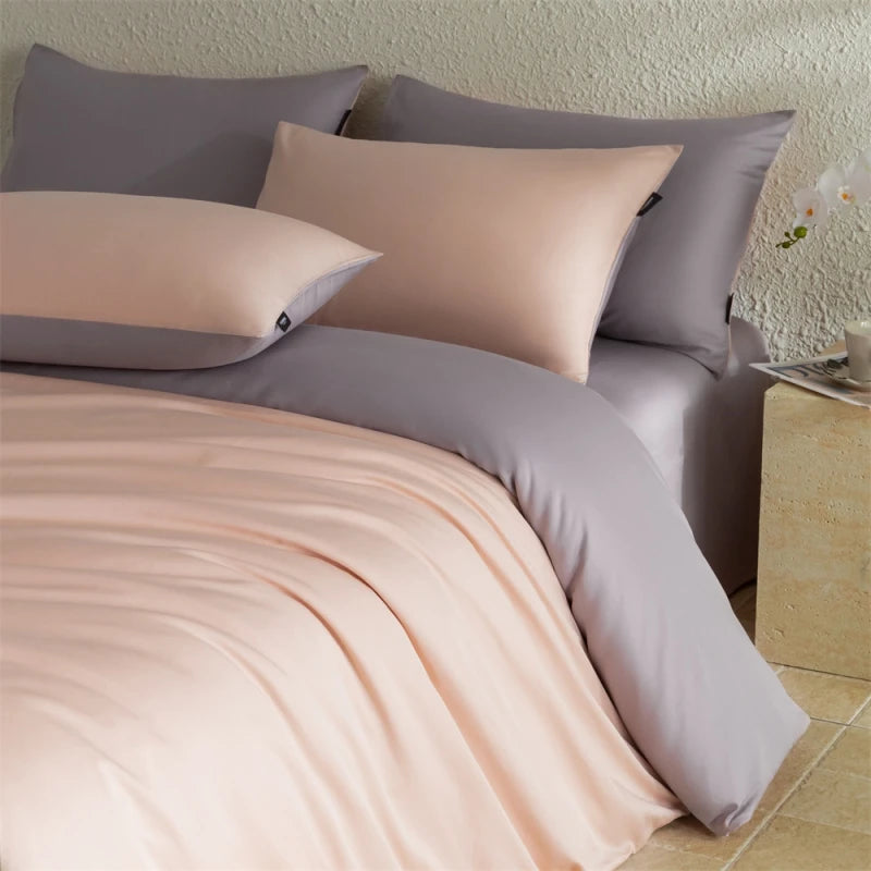 Neatly made bed with pink and gray bedding and pillows.
