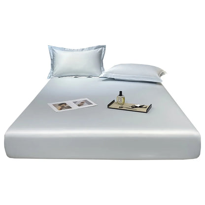 Silver reflective bed sheet set on a bed with a nightstand and photos.