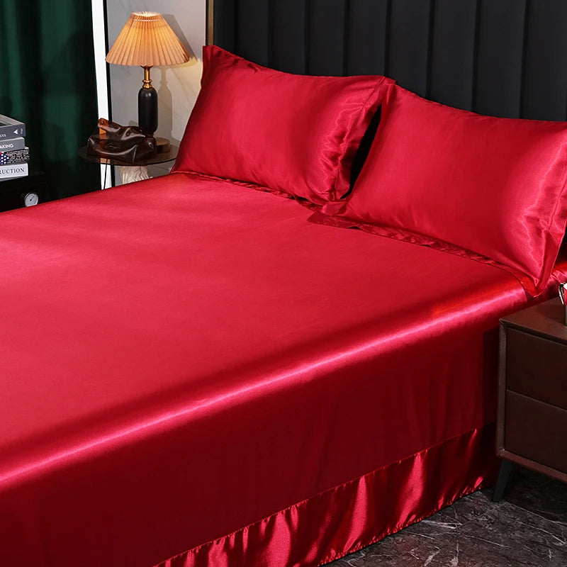 Red satin bedspread on a bed with matching pillows in a bedroom setting.