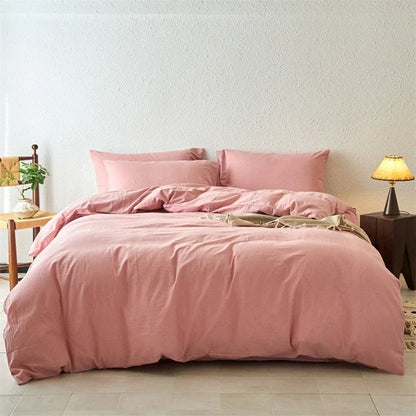 Pink bedding set on a bed in a room with a lamp and plant.