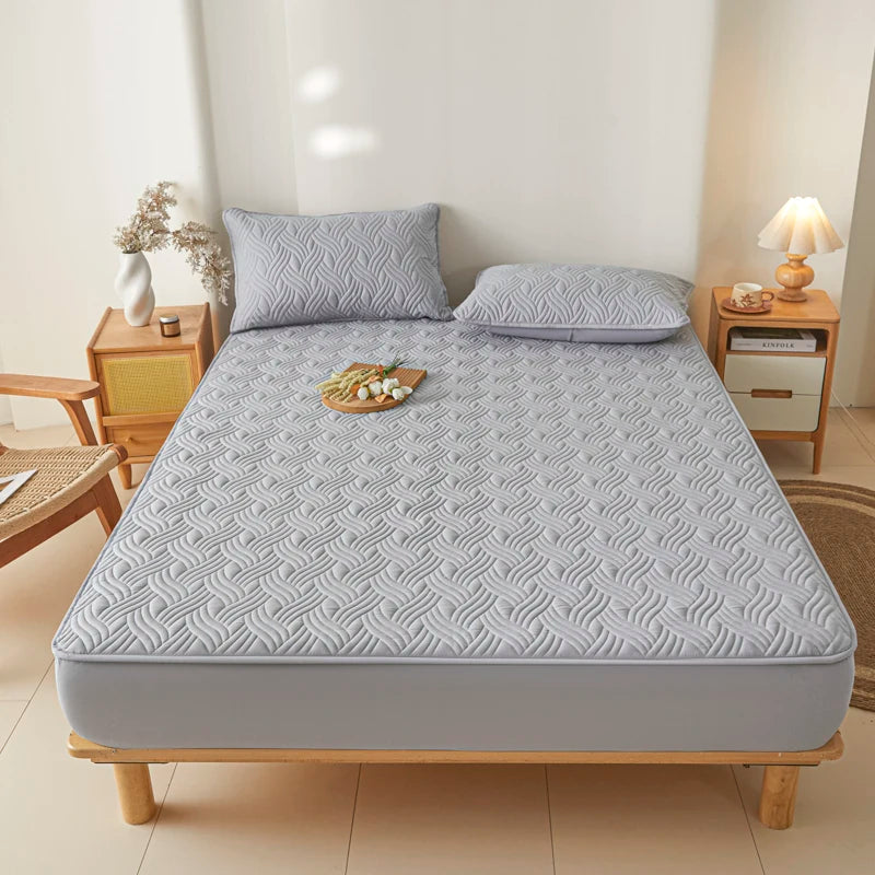 Gray mattress cover on a bed in a bedroom setting with wooden furniture and decor.