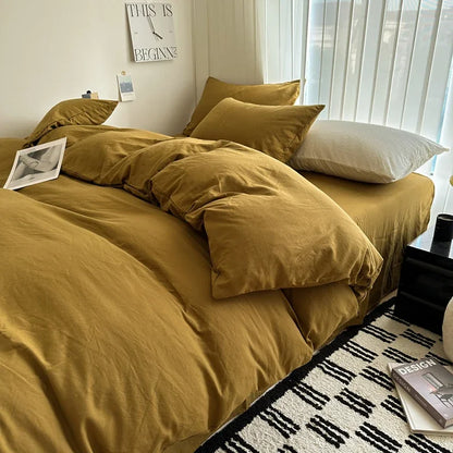 Bed with mustard yellow bedding in a room with a window and decor items.
