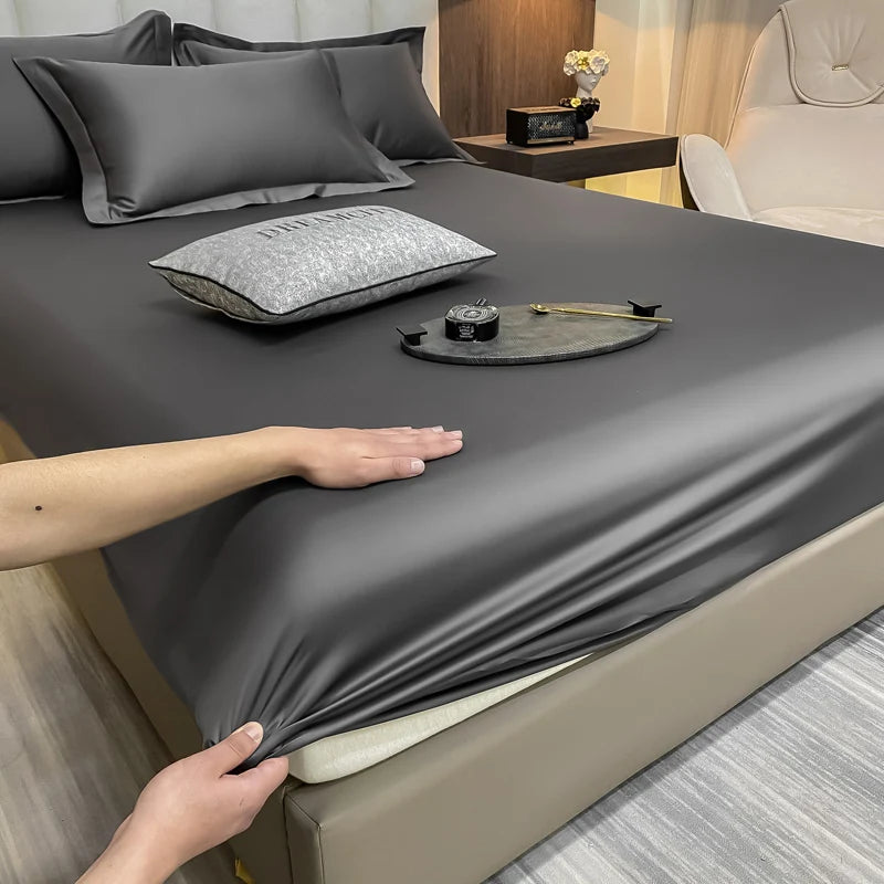 Person adjusting a gray fitted sheet on a bed with pillows and a tray.