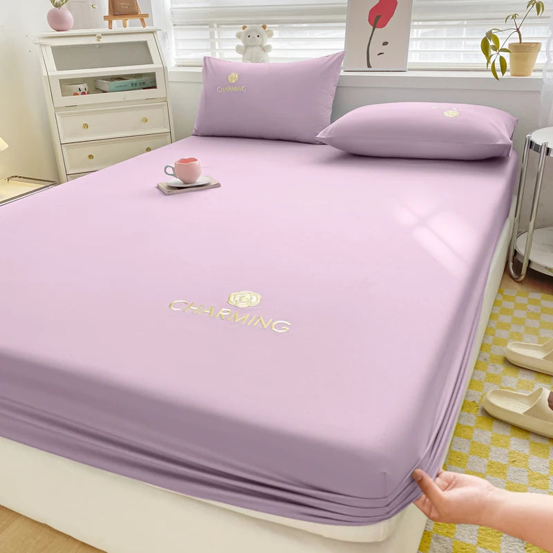 Purple bedsheet with 'CHARMING' branding on a bed in a bedroom setting.