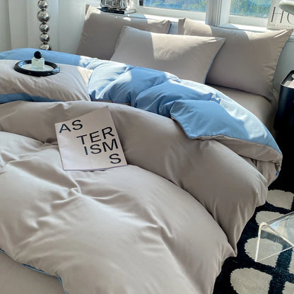 Neatly made bed with gray and blue bedding, featuring a pillow with text.