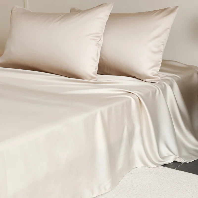 Beige satin sheet set with two pillows on a bed.