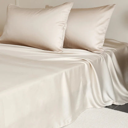Beige satin sheet set with two pillows on a bed.