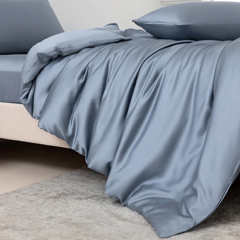 Blue satin sheet set on a bed with a neutral background