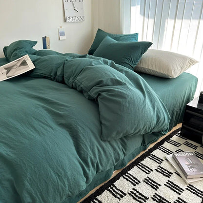 Teal bedspread on a bed in a bedroom with books and decor items.