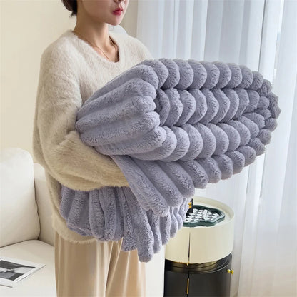 Person holding a large gray knitted blanket in a living room setting.