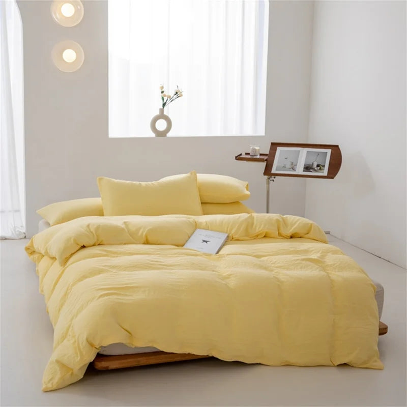 Yellow bedding set on a bed in a minimalistic room with a window and side table.