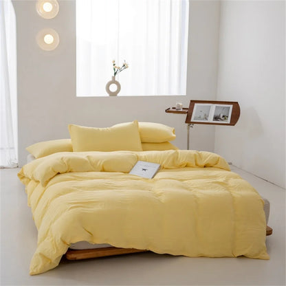 Yellow bedding set on a bed in a minimalistic room with a window and side table.