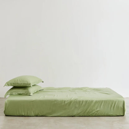 Green bed sheets and pillowcase set on a bed against a white wall.