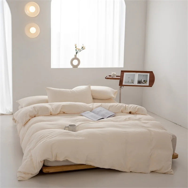 Beige comforter on a bed in a minimalistic room with white walls and a window.