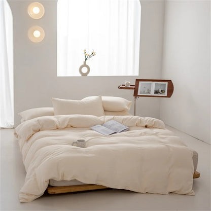Beige comforter on a bed in a minimalistic room with white walls and a window.