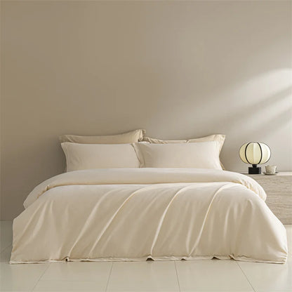Beige bedding set on a bed in a minimalistic room with a lamp and nightstand.