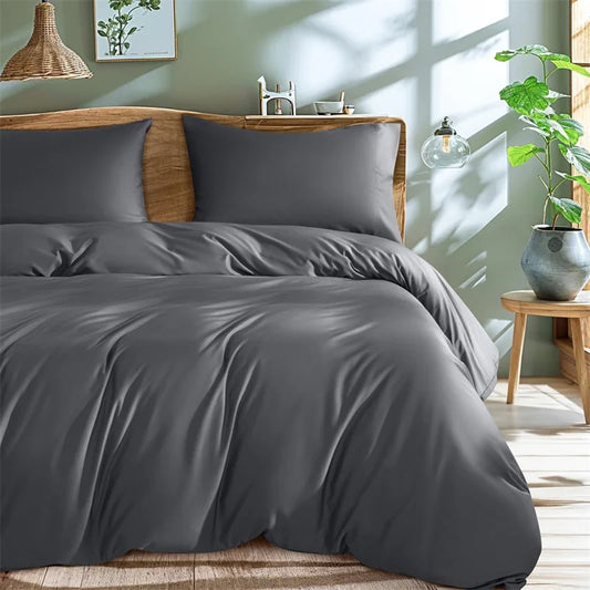 Gray bedding set on a bed in a well-lit bedroom with plants and decor.