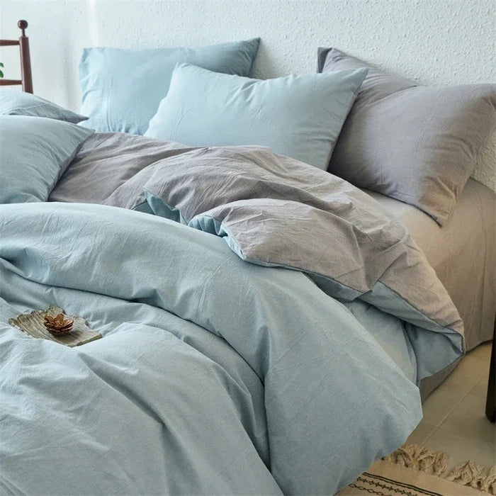 Light blue bedding set on a bed with pillows and a blanket.