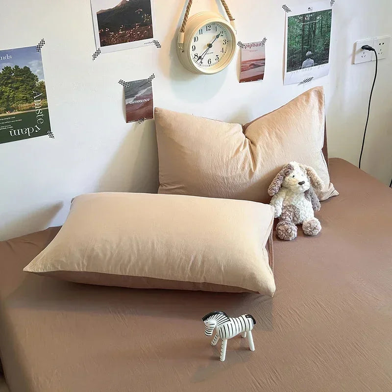Beige pillows on a bed with a stuffed animal and toy zebra, wall clock, and posters in the background.