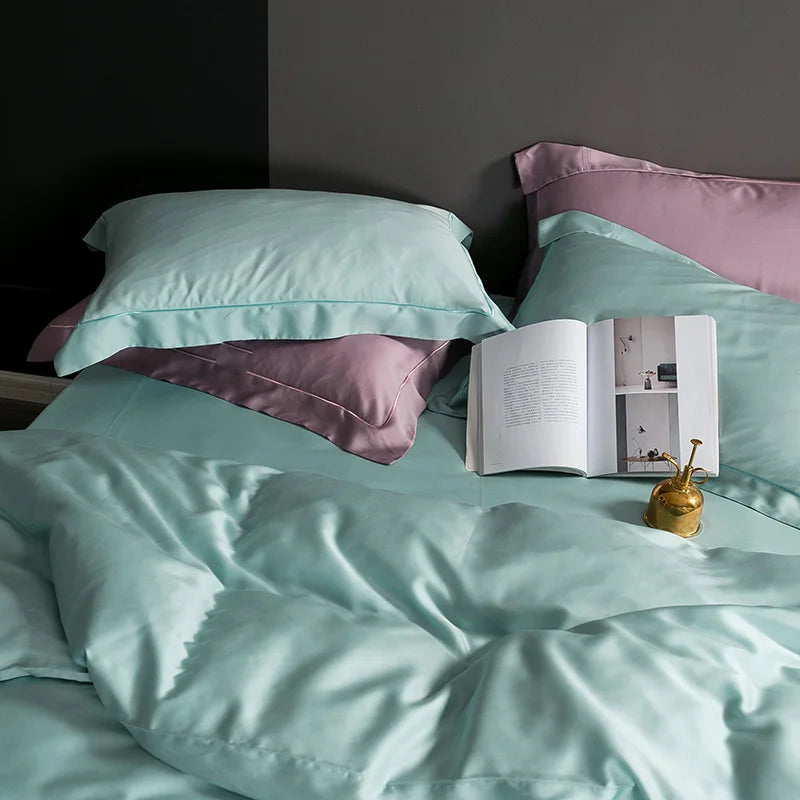 Light green bedding with pink pillows and an open book on a bed.