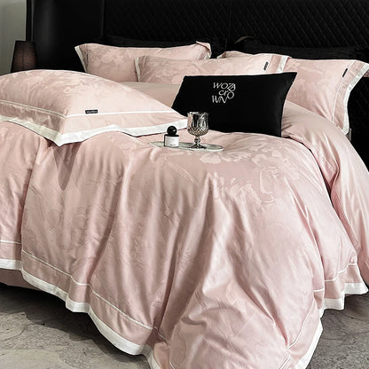 Pink bedspread with decorative pillows and a glass on a bed.